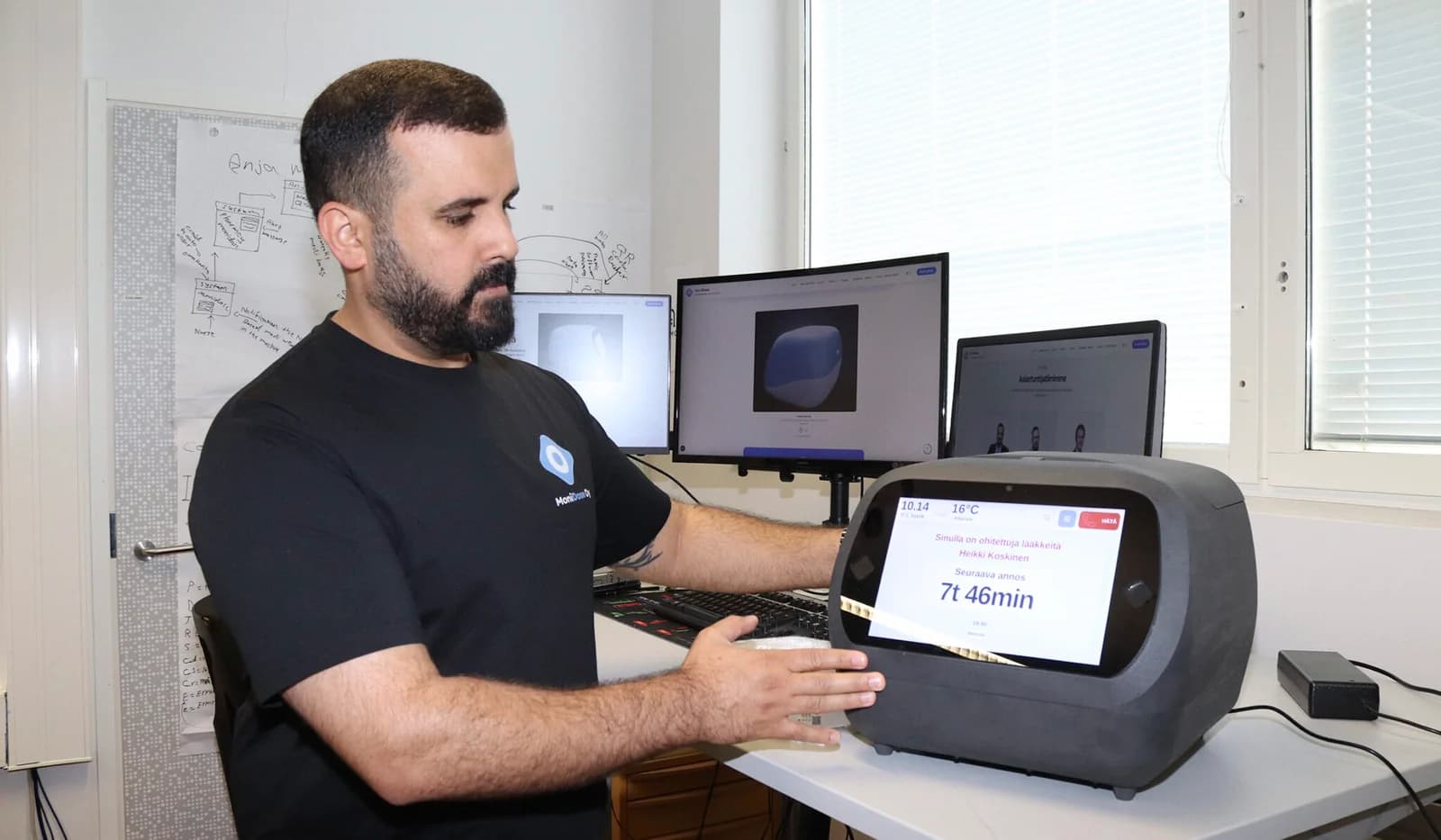 Alaa Salonen showing the MoniDose medication dispenser prototype at his desk